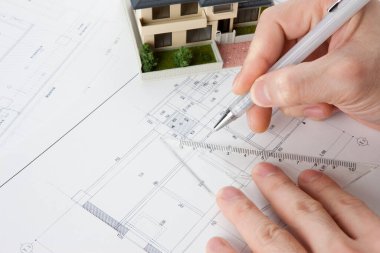 Masasında ev modeli olan bir kalem tutan mimar, yakın plan görünüm             