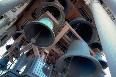 Dışarıda taş sütunların arasında asılı duran büyük metal çanlar.