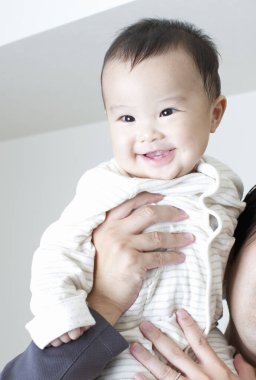 Annenin ellerinde mutlu Japon çocuk, ellerinde küçük oğlunu tutan kadın, yakın plan. 