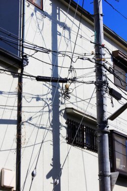 Elektrik kabloları ve gölgelerle kaplı bina duvarı.