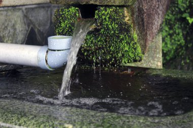 Arka planda su ve boru olan çeşme, kapat
