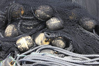 Yıpranmış siyah şamandıraları ve kalın ipleri örten karmaşık balık ağları.