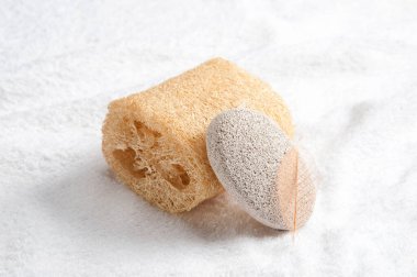 Yumuşak beyaz havlu üzerinde doğal süngerler ve sünger taşı.