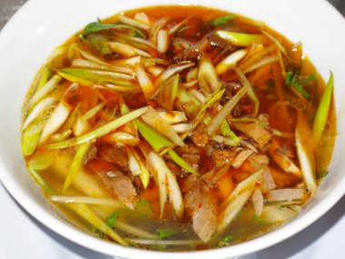 Dilimlenmiş yeşil soğanlı baharatlı çorba ve taze otlar.