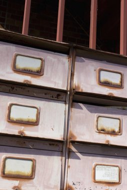 Paslı metal çekmeceler yıpranmış duvara dayanmış.