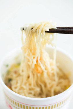 Arka planda yemek çubuğu olan bir kasede erişte.