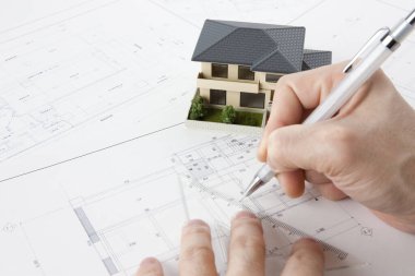 Masasında ev modeli olan bir kalem tutan mimar, yakın plan görünüm             