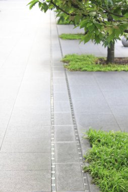 Sokakta yeşil ağaçlar ve çimenler olan yürüyüş yolu