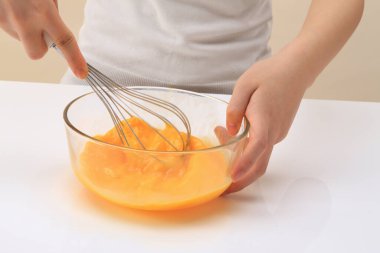 Kadın cam kasede taze yumurta karıştırıyor çırpılmış bir fotoğrafla. 