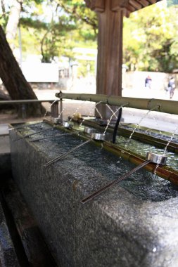 Park Geleneksel Japon Taşı 'ndaki ahşap bir heykelin dikey çekimi ve Ladles ile Bambu Su Arıtma Çeşmesi