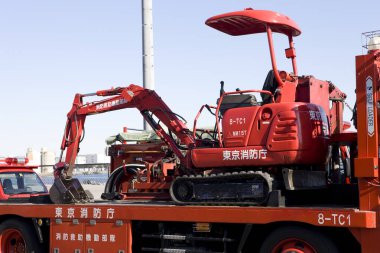 Kırmızı mini kazıcı gündüz vakti düz kamyonun üzerinde dinleniyor.