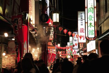 Japonya 'daki şehrin gece manzarası. Mağazalar ve aydınlatmalarla sokakta yürüyen insanlar. 