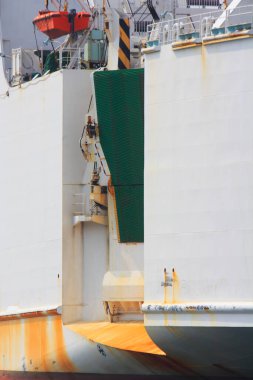 Kargo gemisi gün ışığında limana yanaşıyor. Vinçler ve ekipmanlar yükleniyor.