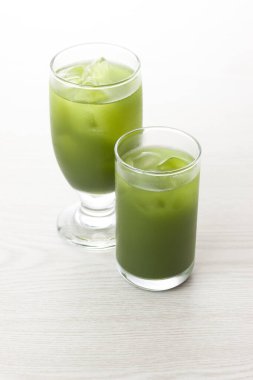 Masada buz küpleri olan bir bardak kibrit yeşil çay. 