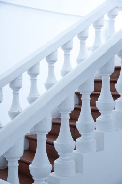 Ahşap merdivenleri ve dekoratif parmaklıkları olan beyaz merdivenler.