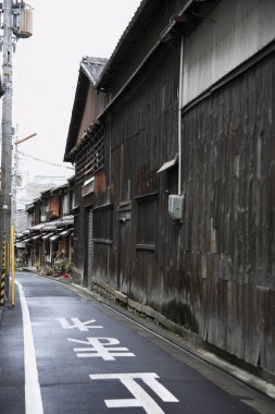Yıpranmış ahşap Japon binalarının yanında dar ve dolambaçlı bir sokak.