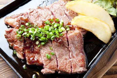 Yanında patates ve salata olan bir biftek.