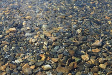 Çakıl taşlarıyla saydam su yüzeyi