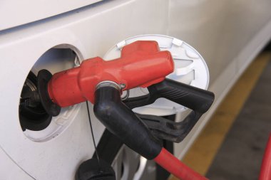 Kırmızı ve siyah yakıt hortumu beyaz bir arabaya bağlıdır.