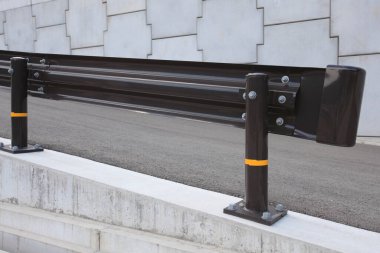 Modern siyah metal korkuluk sistemi kamusal alanda gri bir taş patika boyunca kuruldu.