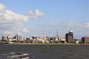 Gündüz vakti açık mavi gökyüzü altında modern mimarinin yer aldığı liman boyunca şehrin ufuk çizgisi
