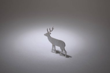 Gri arka planda küçük bir geyik figürü.