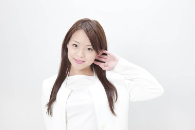 Beyaz arka planda beyaz takım elbiseli şık genç Japon kadın.