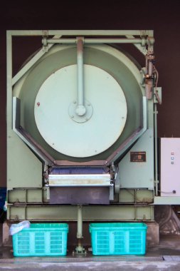 İki turkuaz sepetin arkasında duran büyük endüstriyel makine.