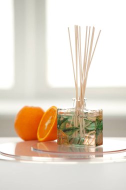 Odada cam parfüm ve portakal şişesi var.