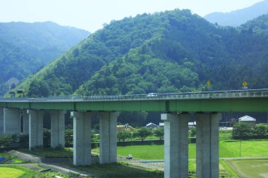 Otoyol köprüsü aşağıdaki engebeli dağ vadisinde uzanır.