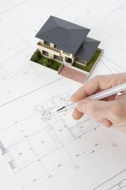 Masasında ev modeli olan bir kalem tutan mimar, yakın plan görünüm             