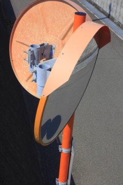 Turuncu trafik aynası parlak güneş ışığı altında boş caddeyi yansıtıyor