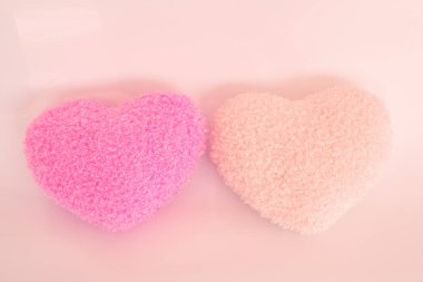 açık arkaplanda kalp şeklinde pembe ve sarı banyo süngerleri.