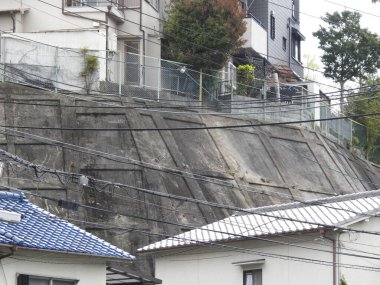 Konut evlerinin yanındaki yamacı destekleyen beton istinat duvarı