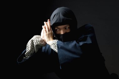 Siyah arka planda ninja kostümlü genç adam.