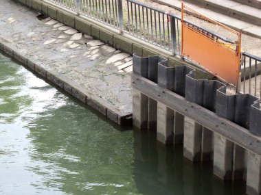 Deniz kenarındaki beton iskele ve metal çitler.