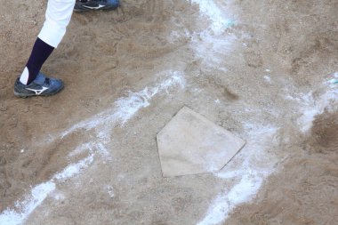 Beyzbol oyuncusu maç sırasında kale levhasının yanında duruyor