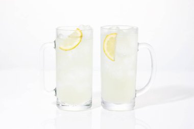 Beyaz arka planda izole edilmiş cam bardaklarda taze limon dilimleri.