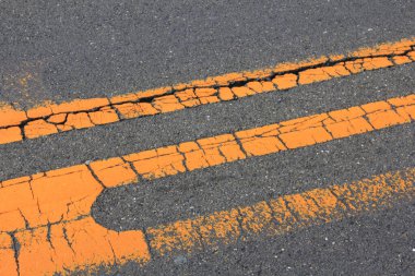 Şehir ortamında asfalt yüzeyinde gündüz saatlerinde çatlak ve soluk yol çizgileri