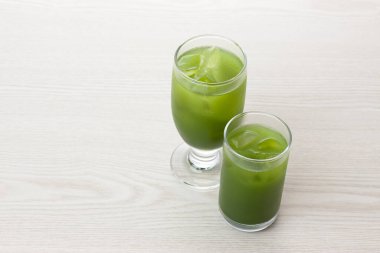 Masada buz küpleri olan bir bardak kibrit yeşil çay. 