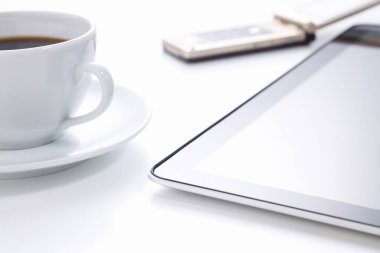 Cep telefonlu tablet bilgisayar ve beyaz arka planda bir fincan kahve.        