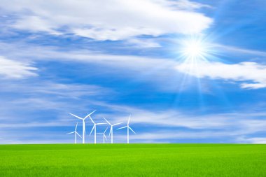 Rüzgâr türbinleri yeşil çimenli çimlerde güneşli mavi gökyüzü arka planında