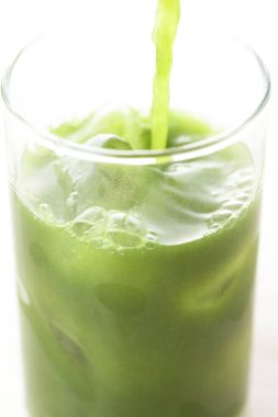 Açık arkaplana dökülen yeşil, taze, sağlıklı organik içeceğin yakın plan görüntüsü.                                          