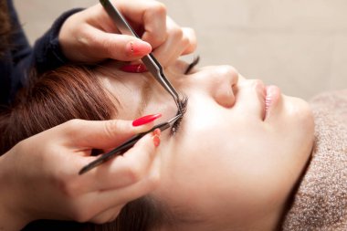 Asyalı kadın güzellik salonunda kirpik taktırıyor.