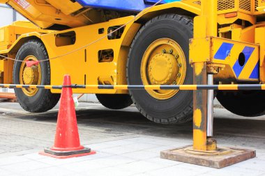 Ağır makineli inşaat sahasında gündüz boyunca sarı bir vinç ve güvenlik konileri de var.