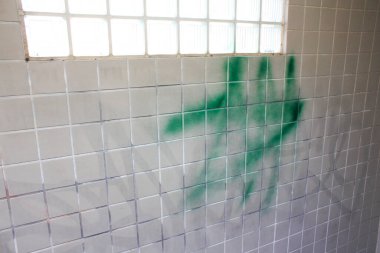 Beyaz fayanslı duvarlar boyunca boyanmış yeşil duvar spreyi.