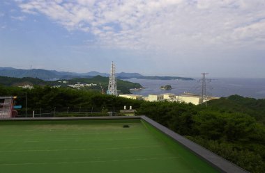 Uzak kıyı şeridi buluşması parçalı bulutlu gökyüzünün altında yemyeşil tepeler