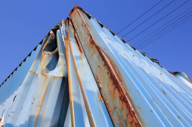 Arka planda mavi gökyüzü olan paslı çelik bir köprü.