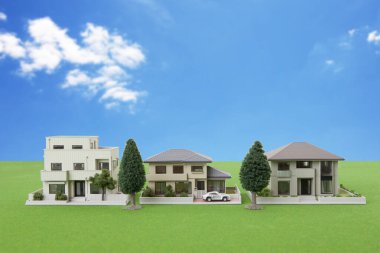 miniature houses models and green trees on grassy meadow.                                              