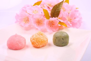 Japon tatlılarının ve açık arkaplanda pembe çiçeklerin yakın plan görüntüsü.        